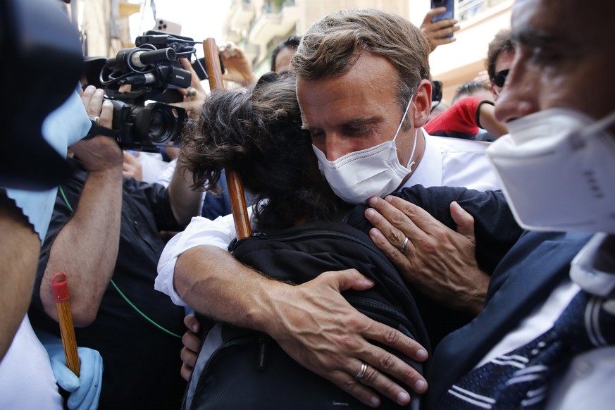 epa08587331 French President Emmanuel Macron hugs a resident as he visits a devastated street of Beirut, Lebanon, 06 August 2020. Macron arrived to Lebanon to show support after a massive explosion on ...