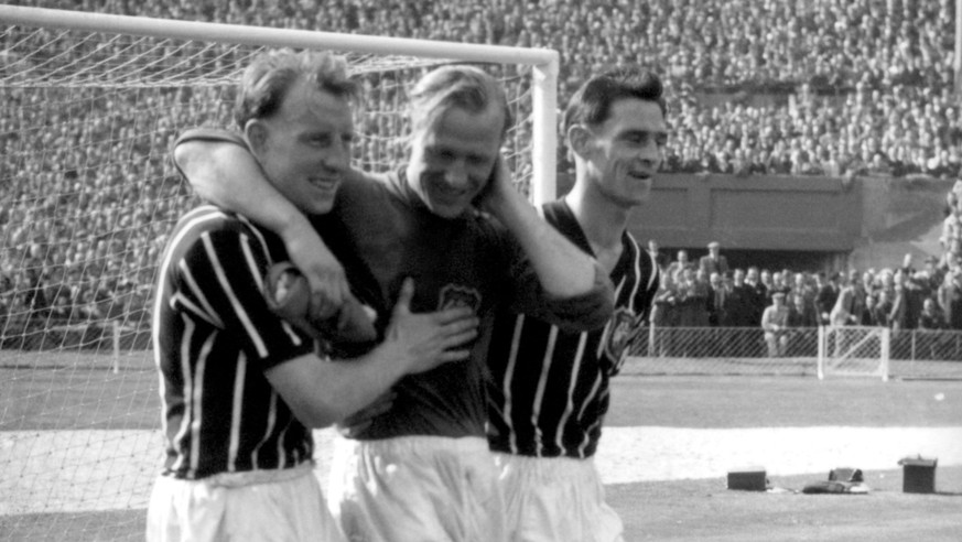 FILE - A May 5, 1956 photo from files of Bernd Trautmann, more commonly known as Bert, Manchester City&#039;s German-born goalkeeper, centre, being assisted from the pitch by two unidentified players, ...