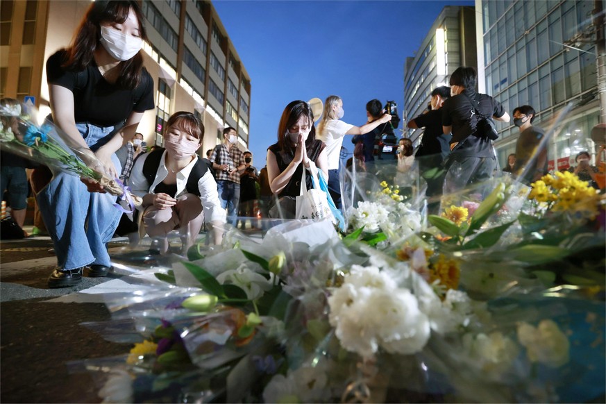 People pray at a makeshift memorial at the scene where former Prime Minister Shinzo Abe was shot while delivering a speech to support the Liberal Democratic Party&#039;s candidate during an election c ...