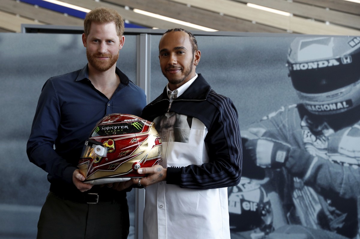 Britain's Prince Harry and Formula One World Champion Lewis Hamilton, right, pose for the media with a helmet belonging to Lewis Hamilton, during a visit to the Silverstone circuit, in Towcester, ...