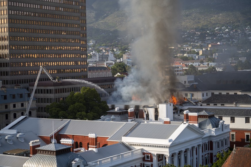 Firemen spray water on flames erupting from a building at South Africa&#039;s Parliament in Cape Town Sunday Jan. 2, 2022. (AP Photo/Jerome Delay)