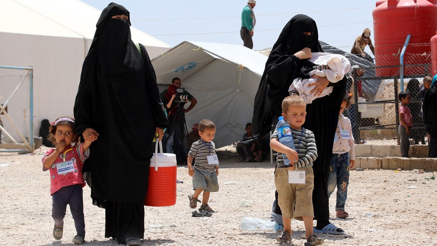 epa07623503 Wives of Islamic state fighters (IS) walk with their children upon their deportation from the al-Hol camp for refugees in al-Hasakah governorate in northeastern Syria on 03 June 2019 (issu ...