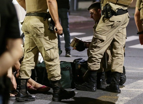 epa08854672 Police collect money left behind by assailants in the aftermath of a bank robbery in Criciuma, Brazil, 01 December 2020. A group of 30 heavily armed and hooded men entered a bank in Criciu ...