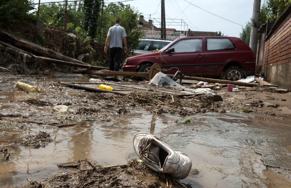 epa05461122 A man walks through the mud in front of his flooded house in the village of Stajkovci, Skopje, The Former Yugoslav Republic of Macedonia on 07 August 2016. At least 15 people have died in  ...