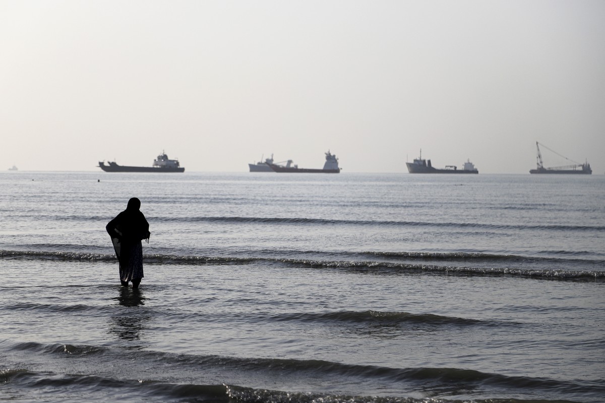 epa13009259 A handout photo made available by Isna News Agency shows an Iranian woman watching cargo ships stuck in the Strait of Hormuz, along the coast of Bandar Abbas, in southern Iran, 01 June 202 ...