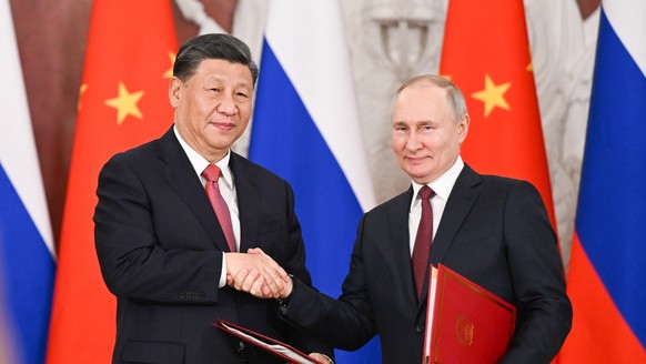 epa10536292 Chinese President Xi Jinping and Russian President Vladimir Putin shake hands after the joint signing of a joint statement by the People's Republic of China and the Russian Federation on &…