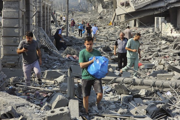 Palestinians walk through the rubble of buildings destroyed by Israeli airstrikes in Gaza City on Tuesday, Oct. 10, 2023. (AP Photo/Hassan Eslaiah)