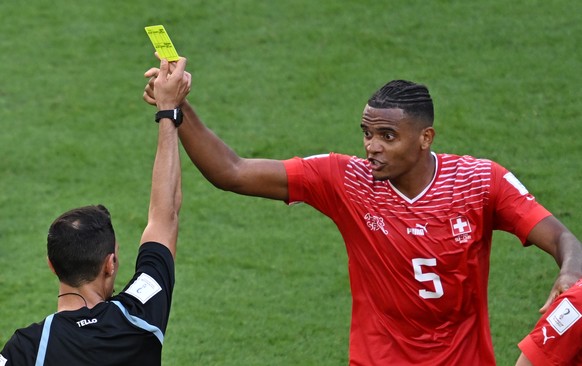 epa10324596 Argentinian referee Facundo Tello shows the yellow card to Manuel Akanji of Switzerland (R) during the FIFA World Cup 2022 group G soccer match between Switzerland and Cameroon at Al Janou ...