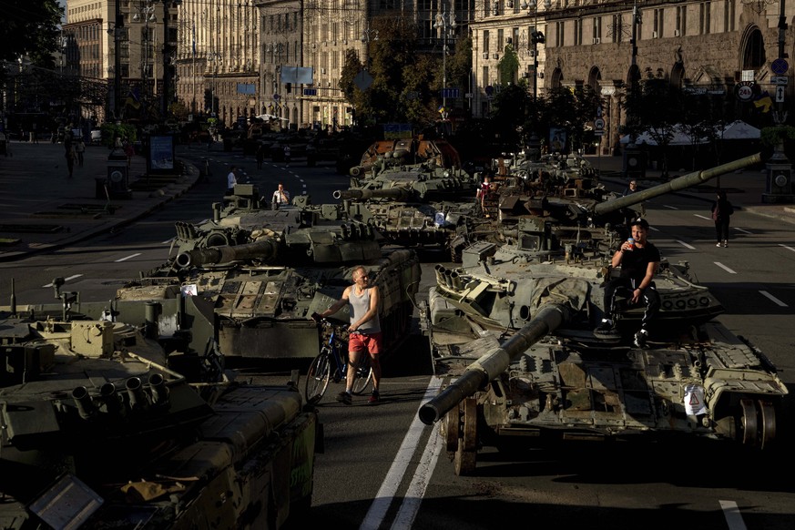 People walk around destroyed Russian military vehicles installed in downtown Kyiv, Ukraine, Wednesday, Aug. 24, 2022. Kyiv authorities have banned mass gatherings in the capital through Thursday for f ...