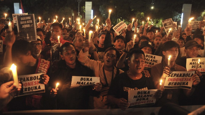 epa10219801 Soccer enthusiasts light candles as they pay condolences to the victims of the soccer match riot and stampede, in Jakarta, Indonesia, 02 October 2022. Indonesia&#039;s National Police Chie ...