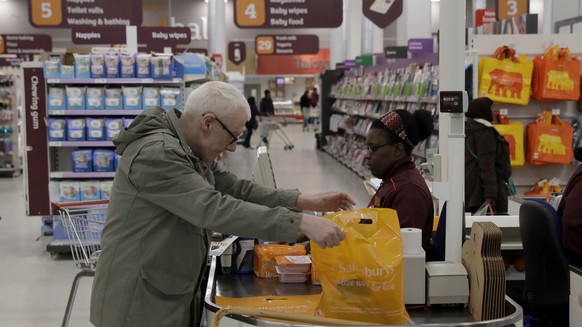 A customer buys shopping at a till in the Sainsbury&#039;s flagship store in the Nine Elms area of London, Monday, April 30, 2018. Sainsbury&#039;s has agreed to buy Walmart&#039;s U.K. unit, Asda, fo ...