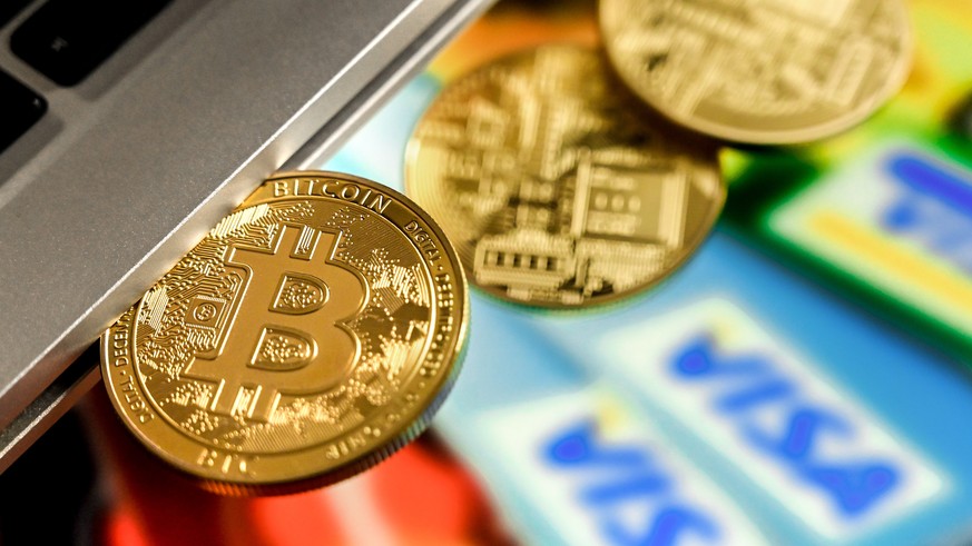 epa09018335 A bitcoin in a slot-in drive reflects in front of a monitor showing credit cards, in Duesseldorf, Germany, 17 February 2021. For the first time, the cryptocurrency Bitcoin has exceeded the ...