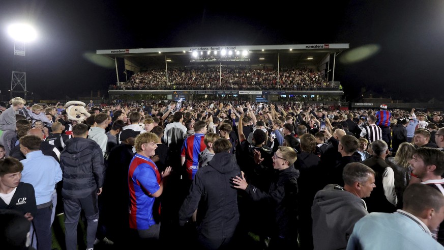 Grimsby Town fans storm the field to celebrate their victory over Manchester United in penalty shootout in an English League Cup second round soccer match, Wednesday, Aug. 27, 2025, at Hill Blundell P ...