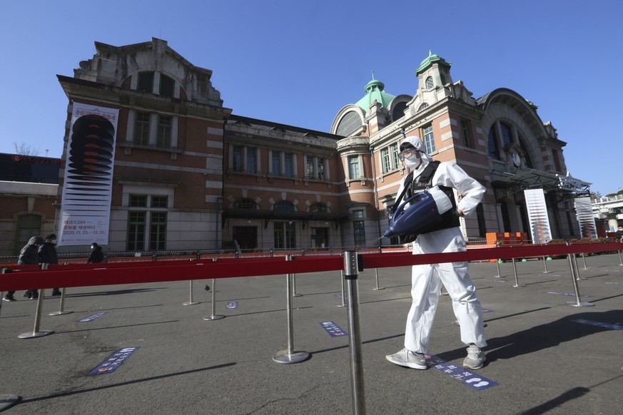 A man wearing protective suits sprays disinfectant as a precaution against the coronavirus near a makeshift clinic in Seoul, South Korea, Saturday, Jan. 2, 2021. South Korea is extending stringent dis ...