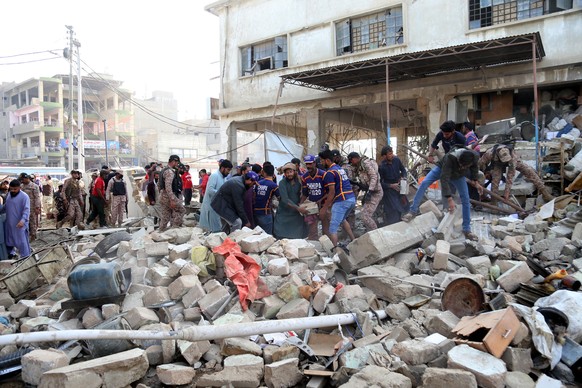 epa09647941 Pakistani security officials inspect the scene of a blast that took place at Paracha Chowk, in Karachi, Pakistan, 18 December 2021. At least 13 people were injured and 11 killed when a exp ...