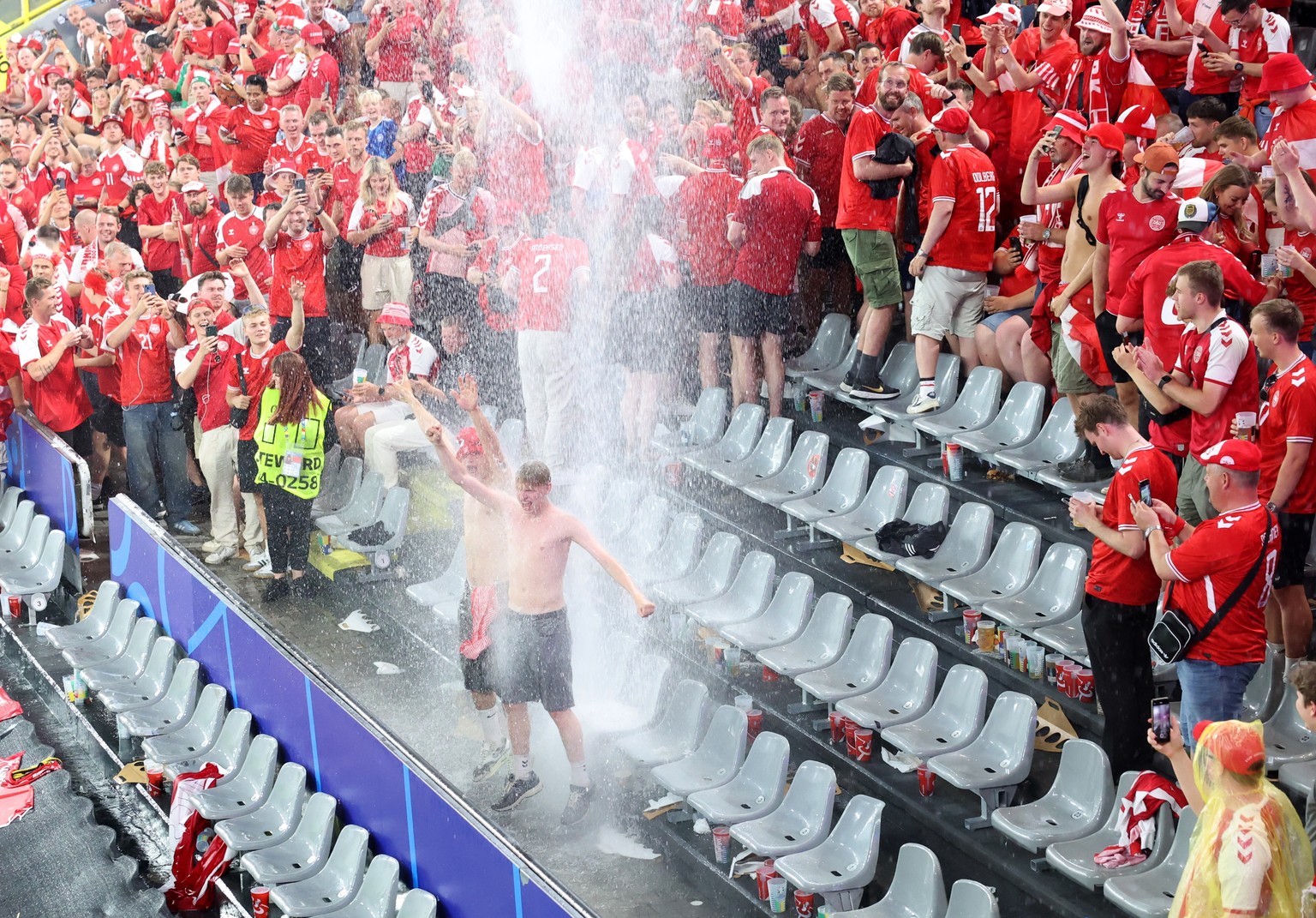 epa11446073 Supporters of Denmark stand under water spilling from the roof due to the weather condition during the UEFA EURO 2024 Round of 16 soccer match between Germany and Denmark, in Dortmund, Ger ...