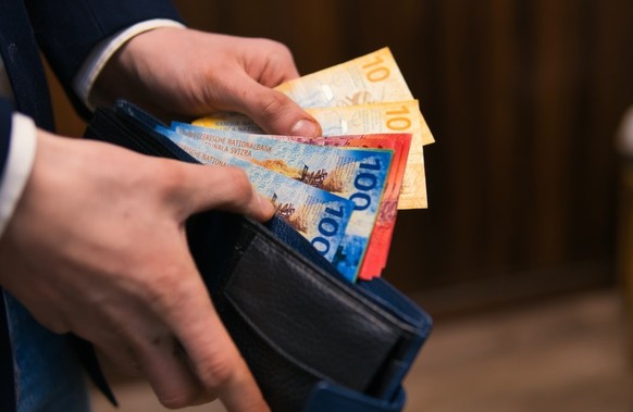 formell gekleideter Mann zählt Schweizer Franken-Banknoten. Konzept für Wirtschaft, Investitionen und Finanzen in der Schweiz