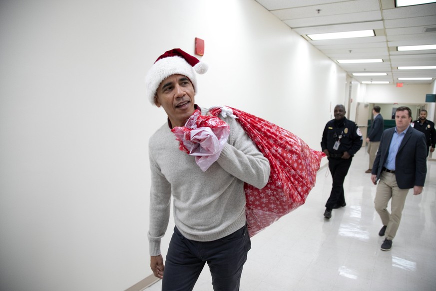 epa07241282 A handout photo made available by the Office of President Barack Obama shows former President Barack Obama (L) delivering gifts to patients at the Children&#039;s National Medical Center i ...