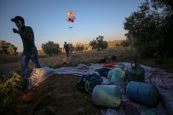 epa08599708 Palestinians wearing masks release a balloon with attached incendiary device to it to Israeli lands near the border between Israel and Eastern Gaza Strip, Gaza Strip, 12 August 2020. EPA/M ...