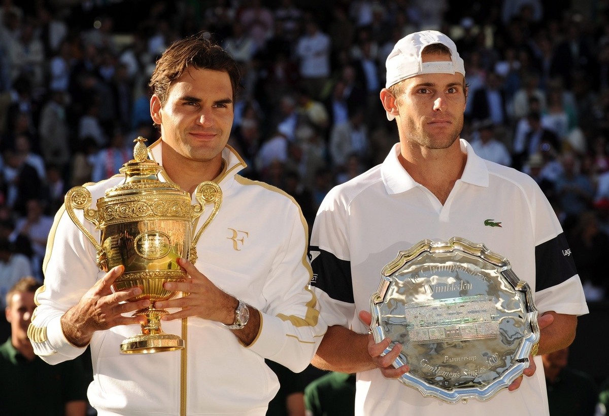 epa01784259 Roger Federer of Switzerland with the championship trophy following his victory over Andy Roddick of the US (R) in their men's singles final match for the Wimbledon Championships at t ...