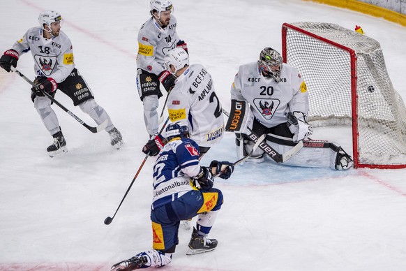 Yannick Zehnder, mitte unten, von Zug schiesst ein Tor gegen Reto Berra, rechts, von Fribourg beim Eishockey Meisterschaftsspiel in der Qualifikation der National League zwischen dem EV Zug und Fribou ...