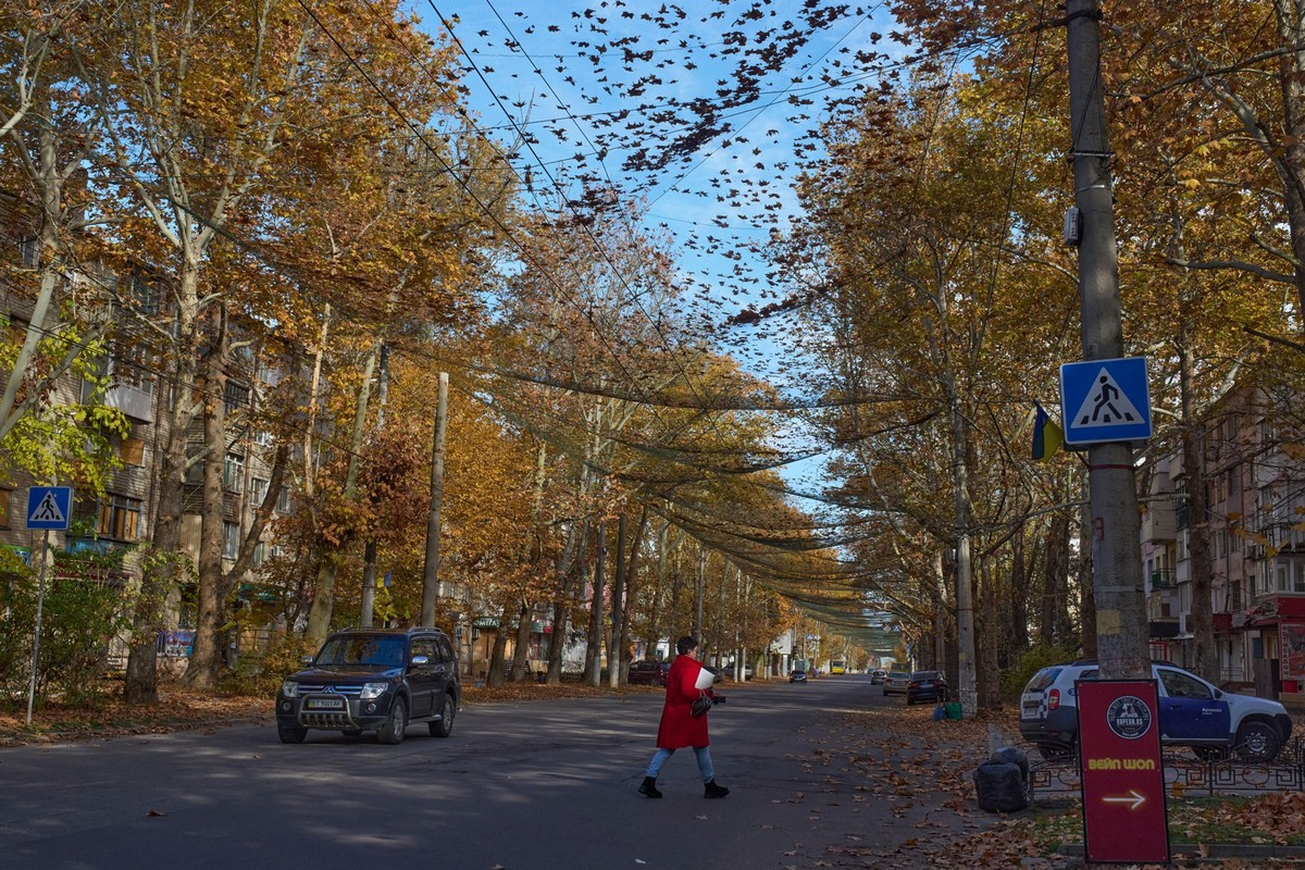 KEYPIX - A local resident crosses the street covered with an anti-FPV-drone net in the frontline city of Kherson, Southern Ukraine, Monday, Nov. 3, 2025. (KEYSTONE/AP Photo/Efrem Lukatsky)