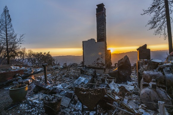 The sun sets over the remains of a house that was destroyed in the Park Fire near Forest Ranch, Calif., Saturday, July 27, 2024. (AP Photo/Nic Coury)