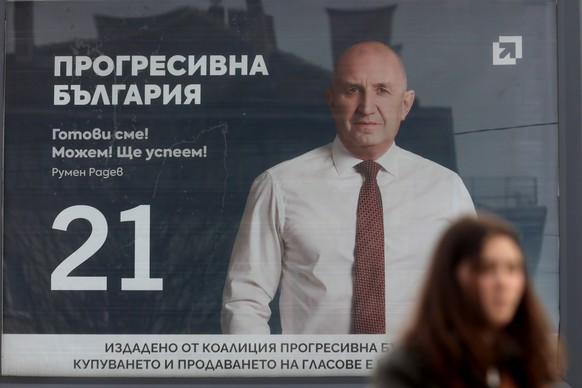 An election poster of former Bulgarian President Rumen Radev is displayed, in Sofia, as a woman passes in front, Thursday, April 16, 2026, with Bulgaria heading into an early parliamentary election. ( ...