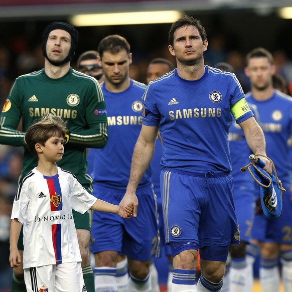 Chelsea&#039;s Frank Lampard, right, holds the hand of a young mascot as he leads his team out prior to their match against Basel in their Europa League semifinal second leg soccer match, at Chelsea&# ...