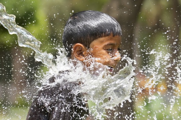A boy cools himself under an irrigation water pipe as northern Indian continues to reel under intense heat wave in Lucknow in the the Indian state of Uttar Pradesh, Wednesday, April 19, 2023. Temperat ...