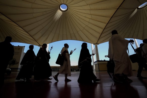 Pilgrims walk under giant umbrellas at the Hajj terminal of King Abdulaziz International Airport in Jeddah, Saudi Arabia, Tuesday, June 20, 2023. Saudi Arabia has ambitious plans to welcome millions m ...