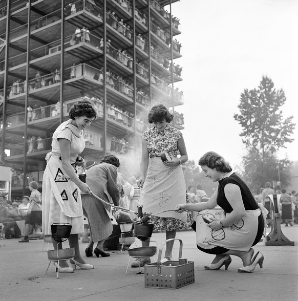 Drei Frauen grillen Cervelats am &quot;Meitli Tag&quot; der Schweizerischen Ausstellung fuer Frauenarbeit SAFFA im September 1958 auf der Landiwiese in Zuerich. (KEYSTONE/PHOTOPRESS-ARCHIV/Hermann Sch ...