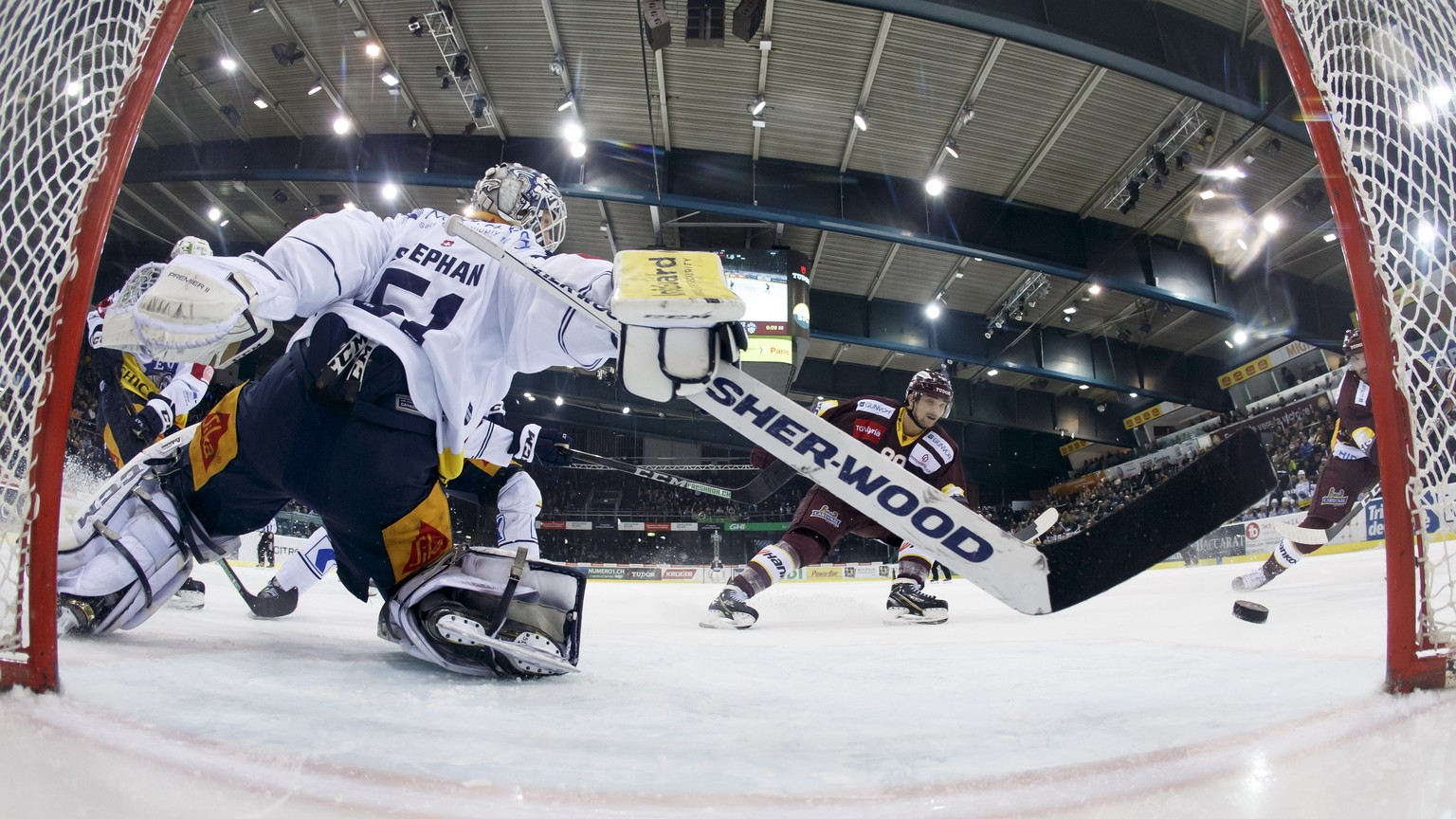 Geneve-Servette&#039;s forward John Fritsche, right, scores the 2:2 against Zug&#039;s goaltender Tobias Stephan, left, past Geneve-Servette&#039;s center Kevin Romy, 2nd right, during a National Leag ...