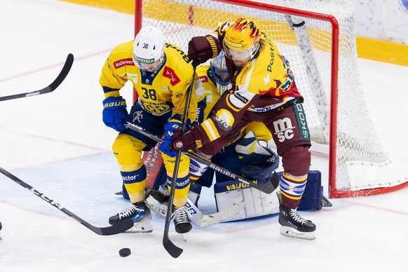 Lukas Frick (HCD), left, vies for the puck with PostFinance Top Scorer Markus Granlund (GSHC), right, past goaltender Sandro Aeschlimann (HCD), centre, during a National League regular season game of  ...