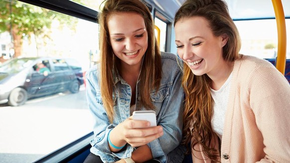 Two young women with smartphones on the bus (symbolic image)