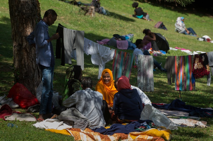 Fluechtlinge essen eine von freiwilligen Helfern der Tessiner Hilfsgruppe Associazione Firdaus verteilte Mahlzeit, in einem Park in der Naehe des Bahnhofs in Como am Freitag, 12. August 2016, in Como  ...