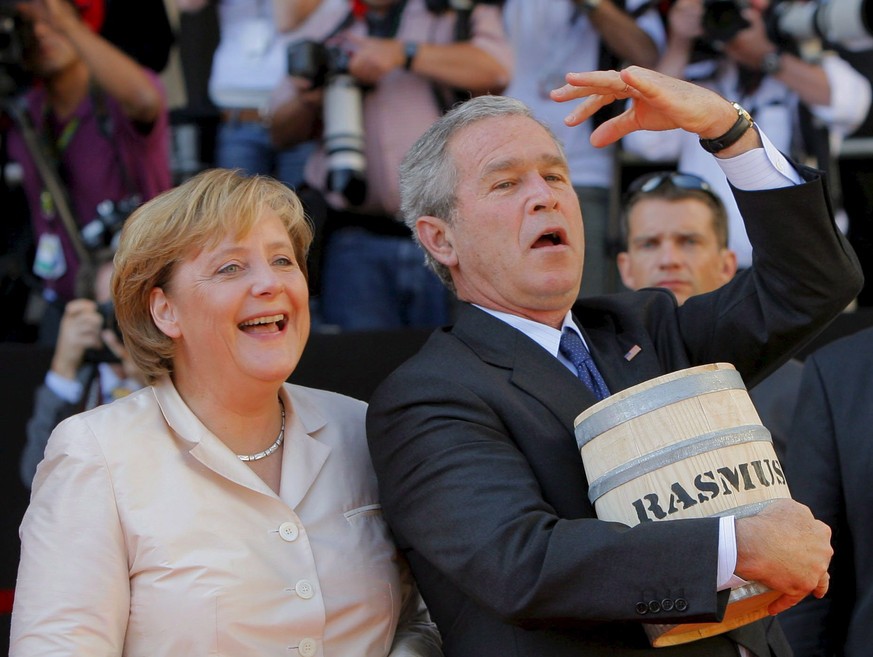 epa08829818 (FILE) - US President George W. Bush (R) gestures with a herring barrel in his arm next to German Chancellor Angela Merkel on the market square of Stralsund, Germany, 13 July 2006 (reissue ...