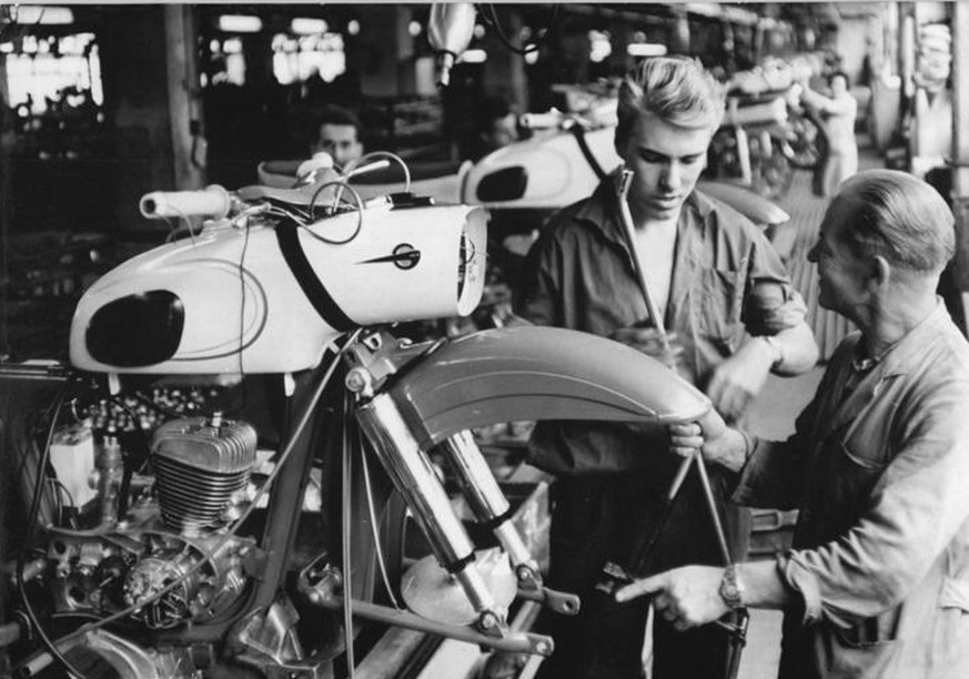 Zentralbild Gahlbeck AV v.3.8.64-3.8.1964 Schwedische Oberschüler weilen gegenwärtig zu einem sechswöchigen Deutschpraktikum im Motorradwerk Zschopau. Meister Walther Leichsenring (rechts) gibt Jören  ...