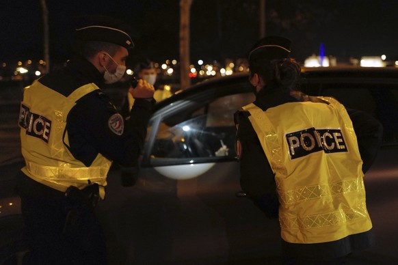 French police officers control a car near the National Assembly, as they enforce a curfew, in Paris, France, Tuesday Dec. 15, 2020. France on Tuesday is lifting a lockdown imposed on Oct. 30, but star ...