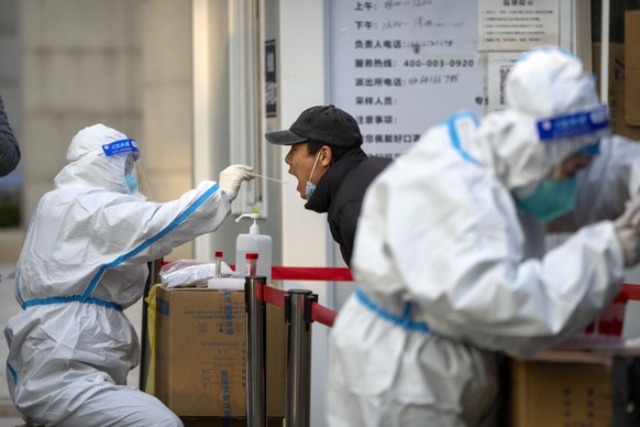 A worker wearing a protective suit wipes a man's throat for a COVID-19 test at a coronavirus testing site in Beijing, Thursday, November 17, 2022. Chinese authorities faced increased public anger on Thursday...