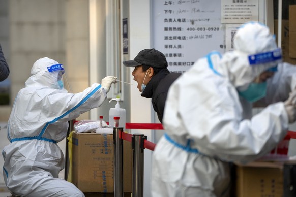 A worker wearing a protective suit swabs a man&#039;s throat for a COVID-19 test at a coronavirus testing site in Beijing, Thursday, Nov. 17, 2022. Chinese authorities faced more public anger Thursday ...