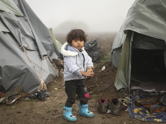 A migrant child poses for a photograph at a makeshift camp housing migrants mostly from Afghanistan, in Velika Kladusa, Bosnia, Tuesday, Oct. 12, 2021. Dozens of children of all ages are among migrant ...