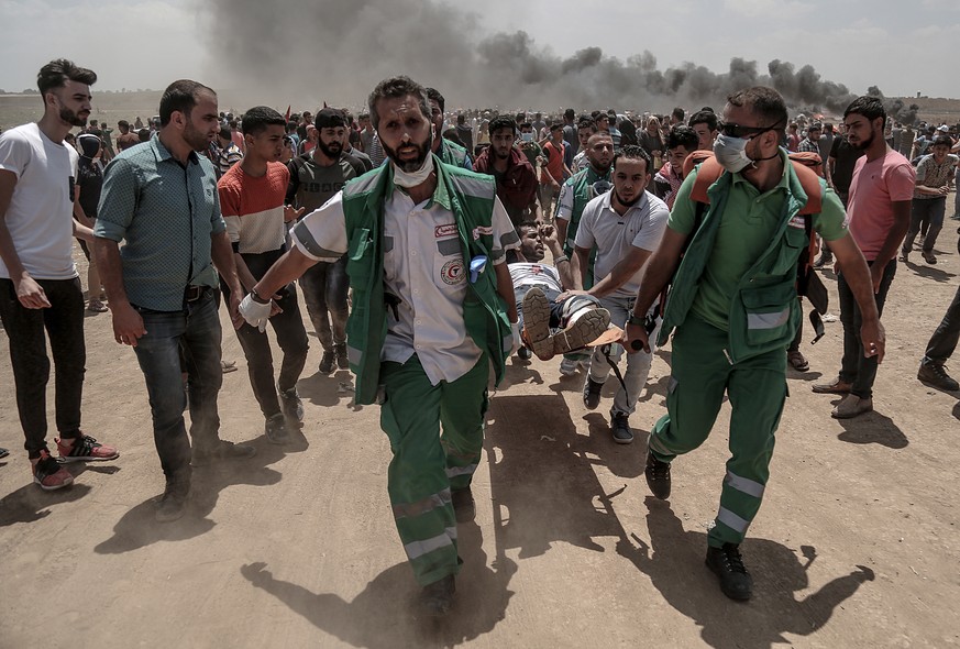 epa06736987 Palestinians medical carry a wounded protester during clashes after protests near the border with Israel in the east of Jabaliya in the northern Gaza Strip, 14 May 2018. 51 Palestinians pr ...