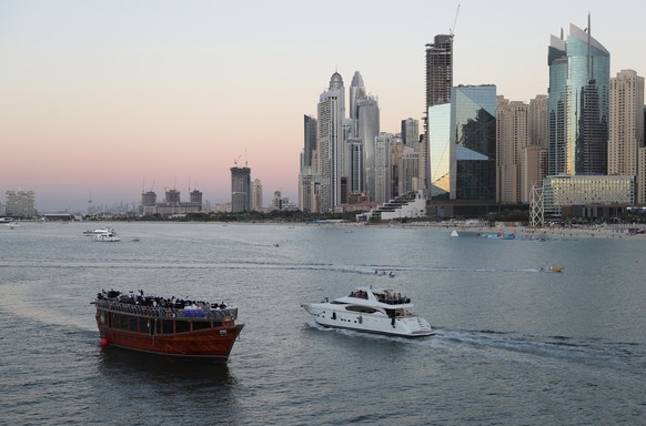 FILE - Tourists enjoy on a yacht as they pass a traditional dhow serving a dinner cruise, in Dubai, United Arab Emirates, Tuesday, Jan. 12, 2021. The globalized city-state of Dubai appears to be in th ...
