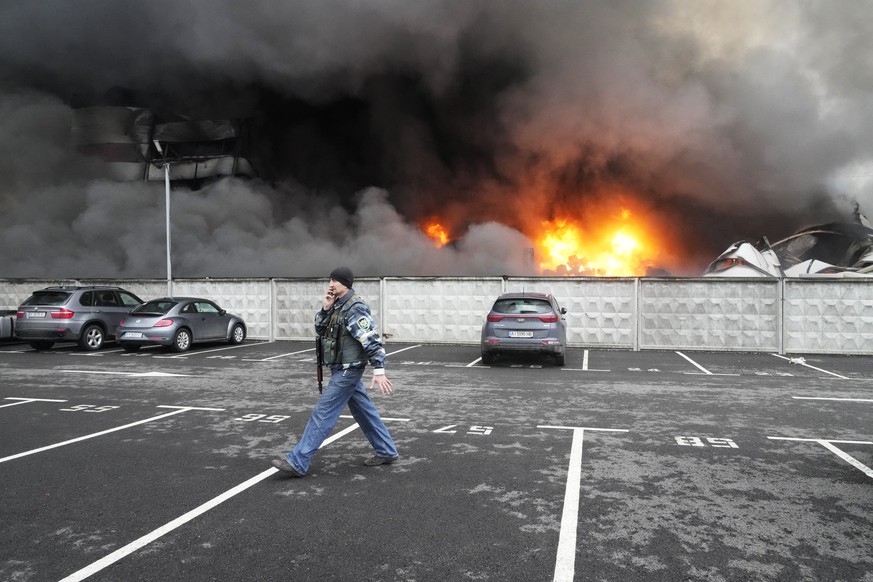 FILE - A Ukrainian serviceman walks past as fire and smoke rises over a damaged logistic center after shelling in Kyiv, Ukraine, March 3, 2022. (AP Photo/Efrem Lukatsky, File)
