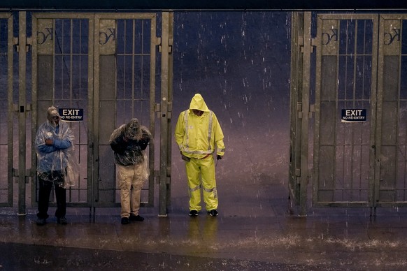 Stadium workers take shelter in an entrance gate after a baseball game between the Kansas City Royals and the New York Yankees Friday, April 29, 2022, in Kansas City, Mo. The game was called after eig ...