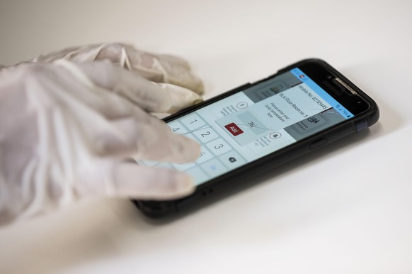 epa08423295 A close up shows a worker demonstrating the use of a mobile phone app, developed by Westlite and the Ministry of Manpower, to log in a temperature reading at the Westlite Papan foreign wor ...