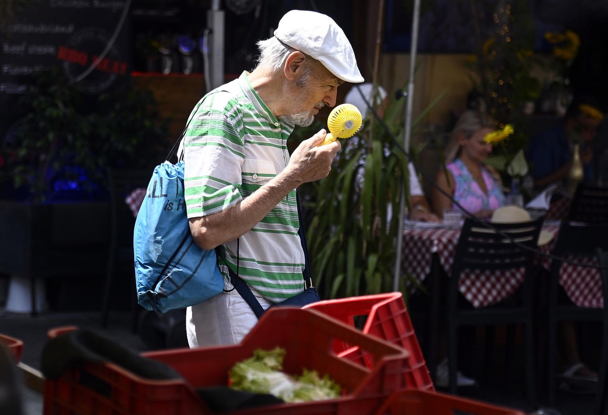 epa10753530 A man uses a fan at the market in Campo de Fiori during a heat wave in Rome, Italy, 18 July 2023. Italy is facing the third heatwave of the summer on 18 July bringing record temperatures.  ...