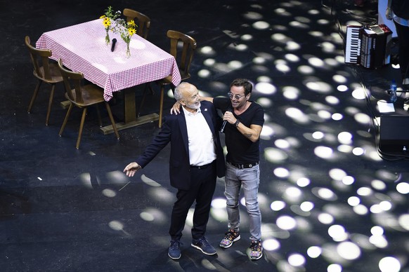 Alt-Bundesrat Ueli Maurer, links, singt mit Saenger Florian Ast beim Wahlauftakt Anlass der SVP Schweiz in der Swiss Life Arena, am Samstag, 26. August 2023 in Zuerich. (KEYSTONE/Michael Buholzer)