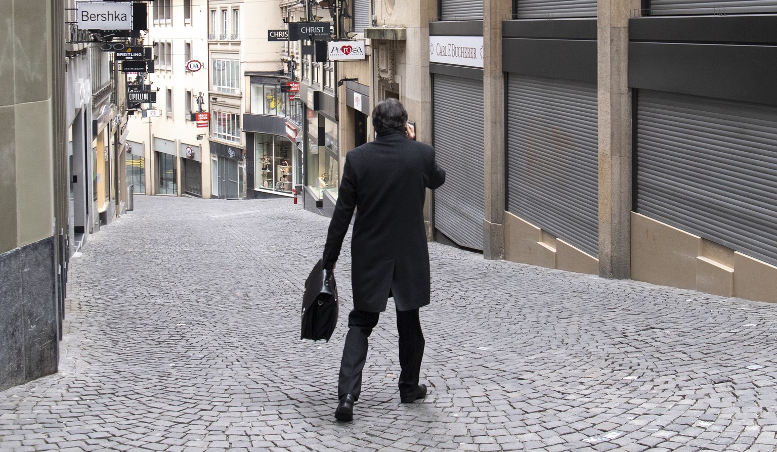 A person is walking down a shopping street (Rue Saint-Francois) as stores are closed during the Covid-19 Coronavirus pandemic in Lausanne, Switzerland, Monday, March 23, 2020. The Swiss authorities pr ...